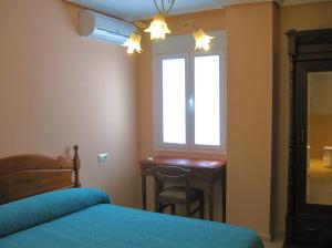 a bedroom with a desk and a bed and a window at Valle del Jerte in Plasencia