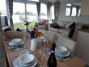 una sala de estar con una mesa con platos y una botella de vino en Aspen Retreat, Haggerston Castle en Cheswick