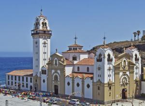 a large building with a clock tower next to the ocean at Casa Elena in Candelaria