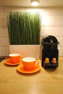 two orange cups on plates next to a toaster at Świdnicka Apartment-City Centre in Wrocław