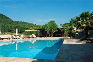 uma grande piscina azul com mesas e cadeiras em Hotel Rural Can Pujolet em Santa Agnès de Corona