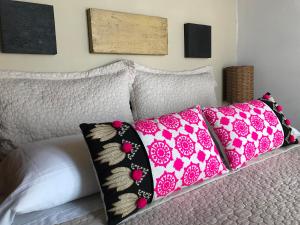een bed met roze en zwarte kussens erop bij Esteños de la Pedrera Posada y Spa in La Pedrera