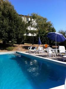 a swimming pool with chairs and an umbrella and a table and chairs at Agriturismo Il Palazzaccio in Galliano