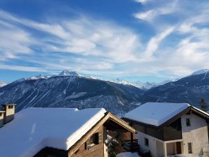 une maison avec de la neige sur le toit et des montagnes dans l'établissement Mollens Chalet, à Mollens