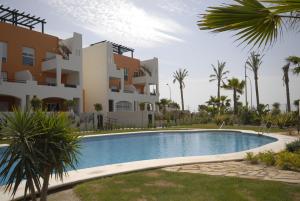 a villa with a swimming pool in front of a building at Apartamentos Paraiso Playa in Vera
