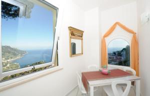 um quarto com uma mesa e uma grande janela em La Dolce Vita Ravello em Ravello