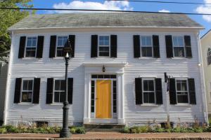 a white house with a yellow door and black shutters at The Sailmaker's House in Portsmouth