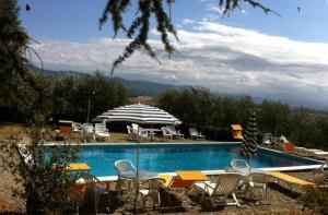 a swimming pool with a bunch of chairs and an umbrella at Agriturismo Il Palazzaccio in Galliano