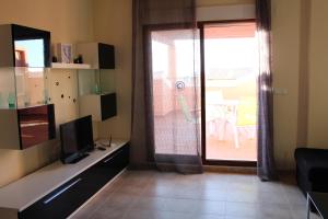 uma sala de estar com uma televisão e uma porta de vidro deslizante em Altos del Sol em Torrevieja