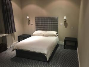 a bedroom with a bed with two tables and two lamps at Crookston Hotel in Glasgow
