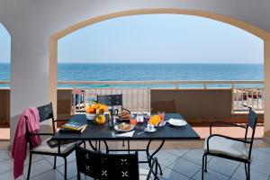a table on a balcony with the ocean in the background at Casa Vacanze Samira in Fondachello