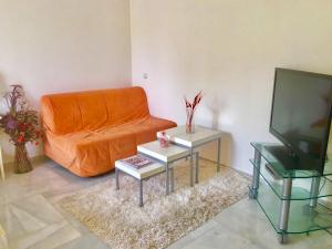 a living room with an orange couch and two tables at Puerto marina in Benalmádena