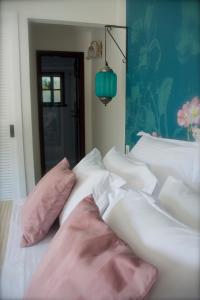 a bed with pink and white pillows on it at Villa Balthazar in Búzios