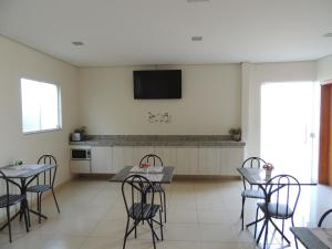 a kitchen with tables and chairs and a tv on the wall at Hotel Viracopos de Indaiatuba in Indaiatuba