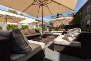 an outdoor patio with couches and umbrellas at Gut Dyckhof in Meerbusch