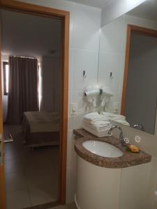 a bathroom with a sink and a mirror at Rosa Branca Facilities Apartamentos in Maceió