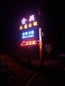 un signe néon avec des écrits asiatiques la nuit dans l'établissement Jin Zu Cottage, à Lugu