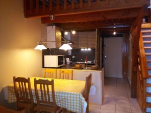 une cuisine et une salle à manger avec une table et des chaises jaunes dans l'établissement Appartements les Bressanes, à Selonnet