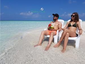 a man and woman sitting in chairs on the beach at Rasdhoo Coralville in Rasdu