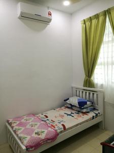 a bedroom with a bed with a blanket and a window at Barakah Homestay in Alor Setar