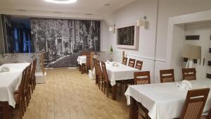 a dining room with white tables and chairs and a painting at Zielony Dworek in Kraśnik