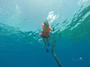 a woman in a life vest swimming in the water at Rasdhoo Coralville in Rasdhoo
