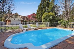 a swimming pool in a yard with two chairs and a house at Oak Cottage - Tudor Village Unit 5 in Bright