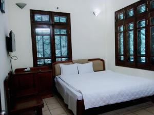 a bedroom with two beds and a table and windows at Ngoc Son Tam Dao Hotel in Tam Ðảo