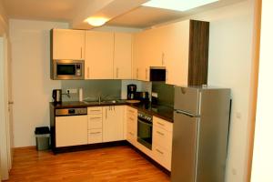 La cuisine est équipée de placards blancs et d'un réfrigérateur en acier inoxydable. dans l'établissement Appartement Neusiedl am See mit Dachterrasse, à Neusiedl am See