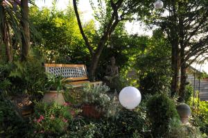 un giardino con panchina, piante e statua di Les chambres du Chat Perché a Le Havre