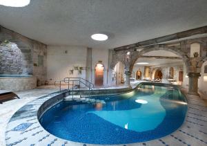 a large swimming pool in a building with an archway at Anatolian Houses Cave Hotel & SPA in Göreme