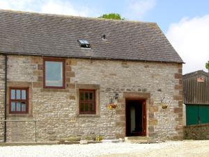 an old stone house with a green door and windows at Nuffies Cottage in Elton