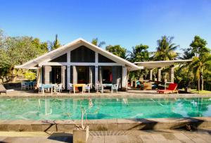 a house with a swimming pool in front of it at Le Mirage Villa Santai in Lovina