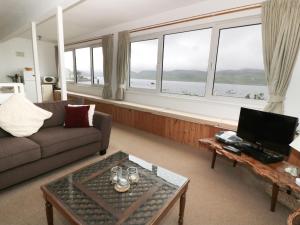 a living room with a couch and a table and windows at Top Flat in Tighnabruaich