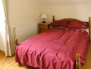 a bedroom with a bed with a red bedspread at Nuffies Cottage in Elton