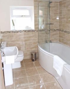 a bathroom with a toilet and a tub and a sink at Rowan Studio in Great Witcombe