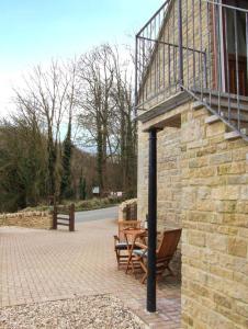 a patio with two chairs and a table next to a building at Rowan Studio in Great Witcombe