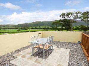 a table and chairs on a patio with mountains in the background at Fell View Cottage in Bootle