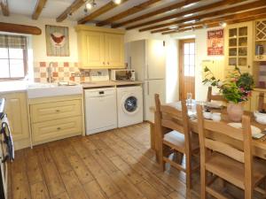 a kitchen with a table and a sink and a dishwasher at Fell View Cottage in Bootle