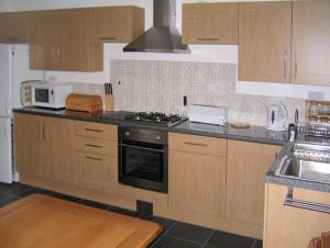 a kitchen with wooden cabinets and a stove top oven at Penrallt Cottage in Y Felinheli