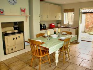 une cuisine avec une table et des chaises dans l'établissement Beaconsfield Cottage, à Briston