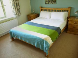 a bedroom with a bed with a green and blue blanket at Beaconsfield Cottage in Briston