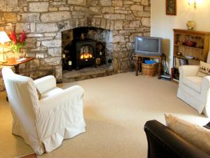 a living room with a stone fireplace and a tv at Pen y Parc in Meliden