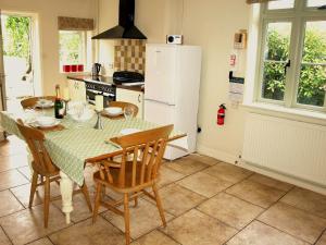 a kitchen with a table and chairs and a refrigerator at Beaconsfield Cottage in Briston +6 photos