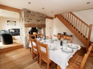 a dining room with a table and a fireplace at Stoneycroft Barn in Langsett