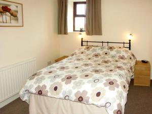 een slaapkamer met een bed met een bloemenpatroon bij Penrallt Cottage in Y Felinheli