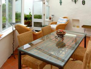 uma sala de jantar com uma mesa de vidro e cadeiras de vime em Pen y Parc em Meliden