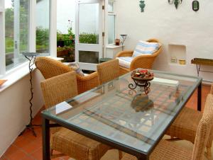 a dining room with a glass table and wicker chairs at Pen y Parc in Meliden