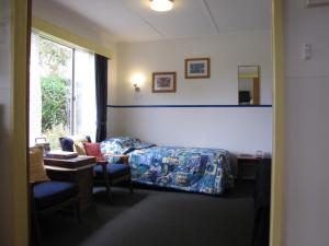 um quarto com uma cama, uma secretária e uma janela em King Island Accommodation Cottages em Naracoopa