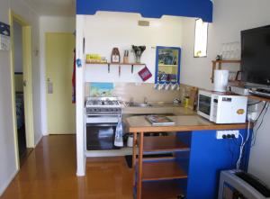 a small kitchen with a stove and a counter at King Island Accommodation Cottages in Naracoopa